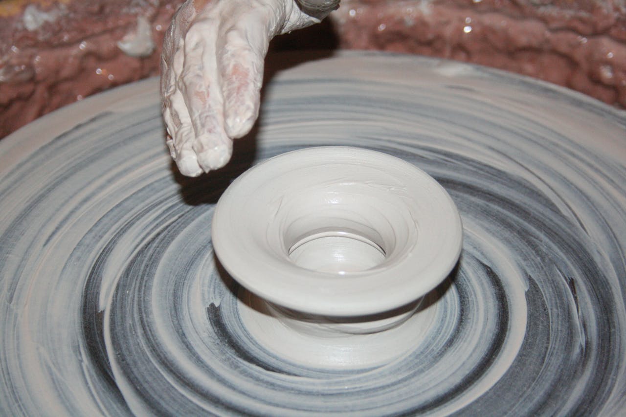 Home Artisan shapes clay on a spinning pottery wheel, creating a ceramic bowl.